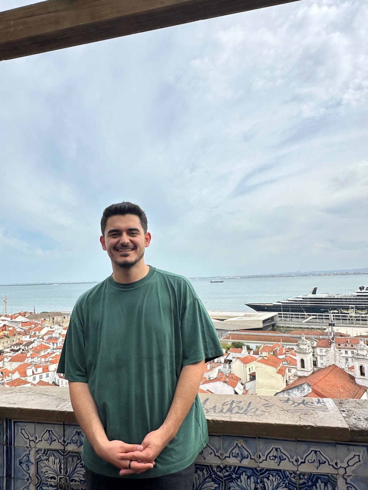 Yasir Balcı at an Alfama viewpoint, Lisbon roofs behind